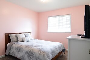 Un dormitorio con cama, escritorio y ventana.