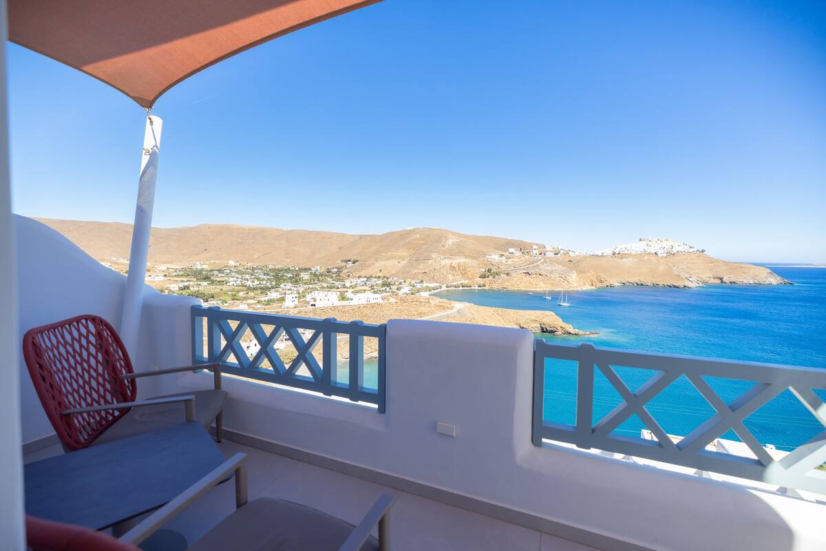 A balcony with a view of the sea and hills.