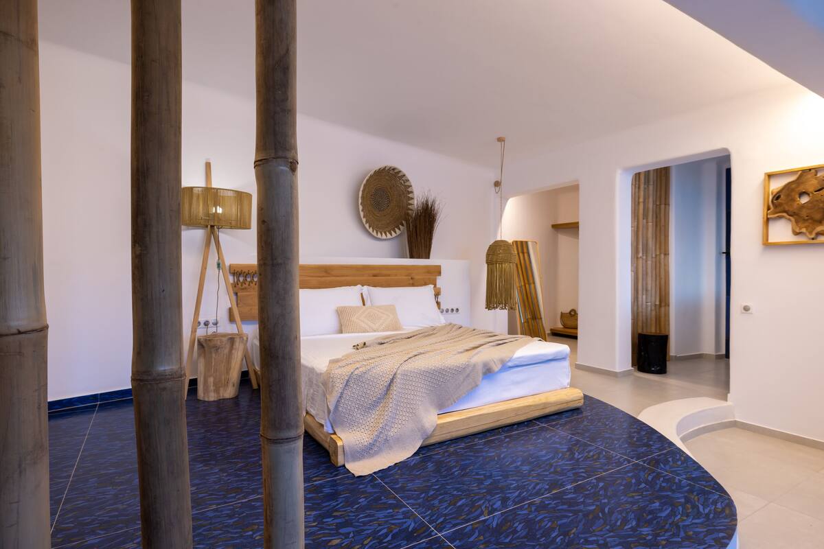 A modern bedroom with a wooden bed, a blue patterned floor, and a large window.