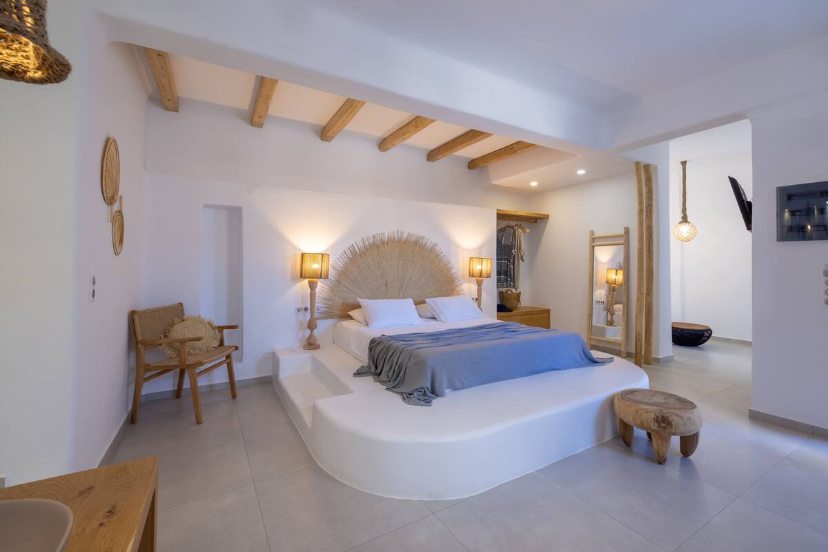 A modern bedroom with a curved bed, wooden beams, and a large mirror.