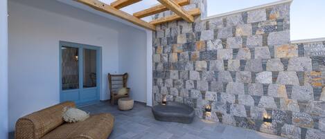 Un área de estar al aire libre con pared de piedra, vigas de madera y una puerta azul.