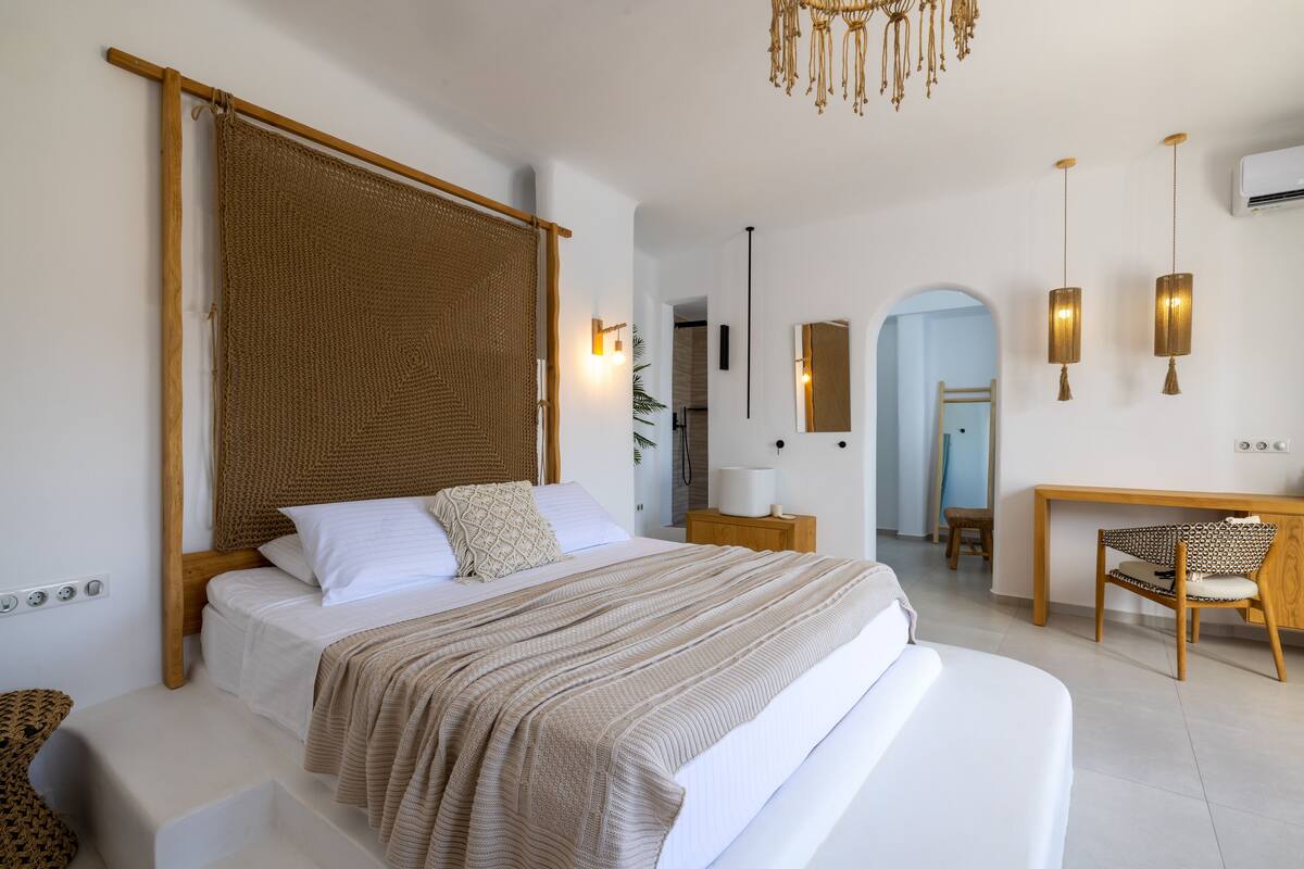 A bedroom with a large bed, a wooden headboard, a desk, and a chair.