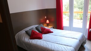 A double bed with a white and gray patterned duvet, two red pillows, and a bedside table with a red lamp. - Air-conditioned vacation home with a pool: Gite Etape Cathare (Duilhac-sous-Peyrepertuse)