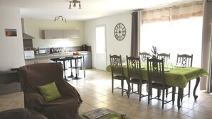 A living room with a brown sofa, a dining table with chairs, and a kitchen in the background. - Air-conditioned vacation home with a pool: Gite Etape Cathare (Duilhac-sous-Peyrepertuse)