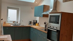 A modern kitchen with teal cabinets, a skylight, a built-in oven, and a coffee maker. - Country house with jacuzzi (Cheilly-lès-Maranges)