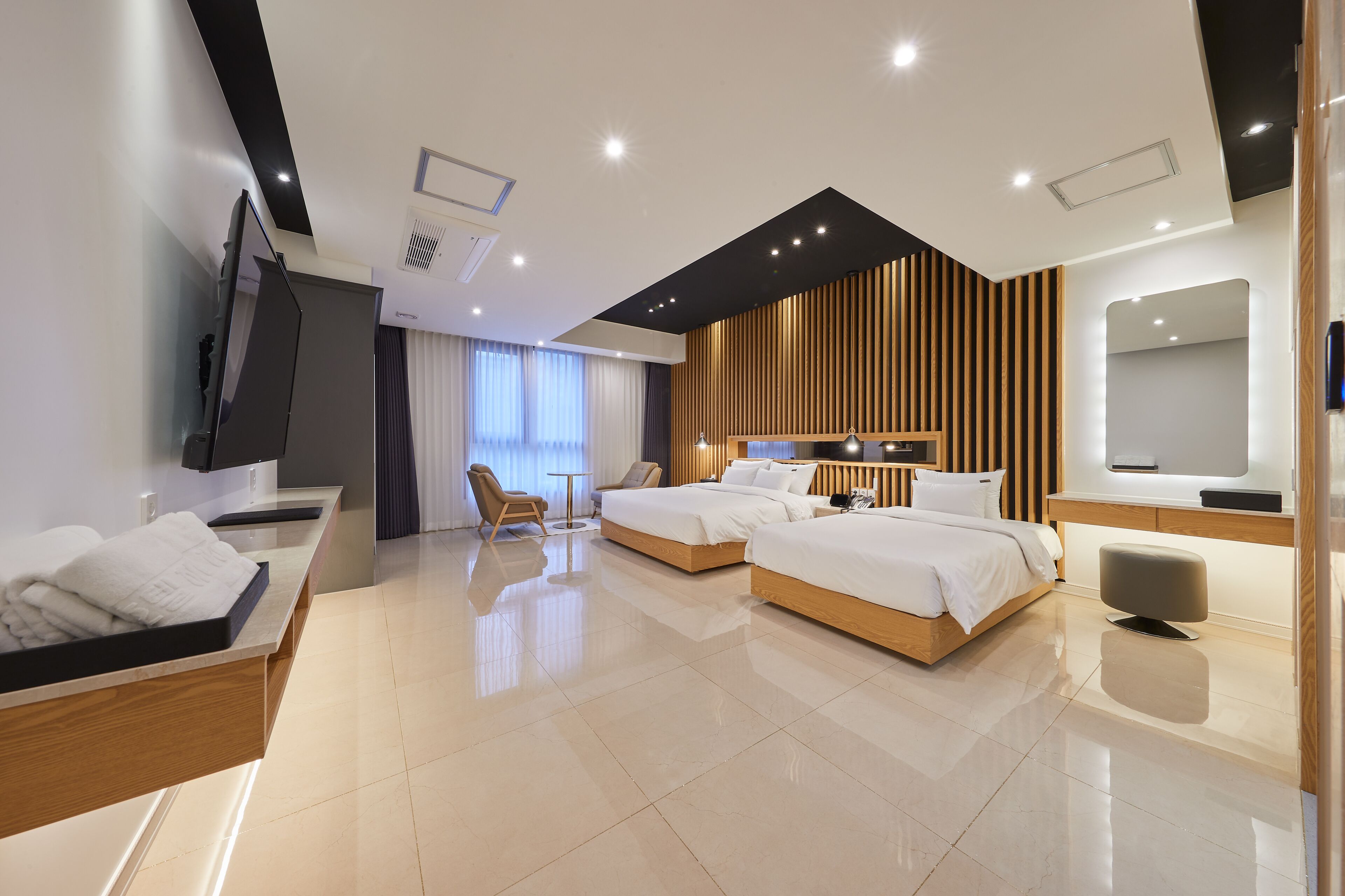 A modern hotel room with a large bed, a desk, a chair, and a TV.