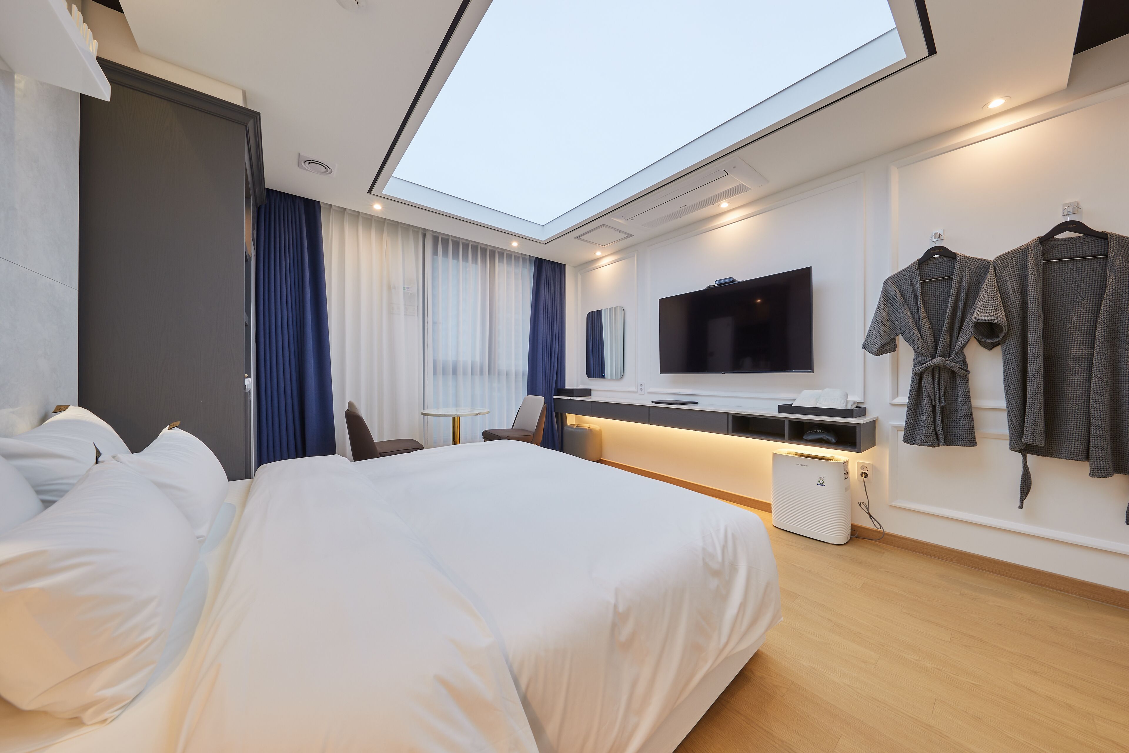 Camera d'albergo moderna con un letto grande, una scrivania con TV a schermo piatto, un'area salotto e un lucernario.