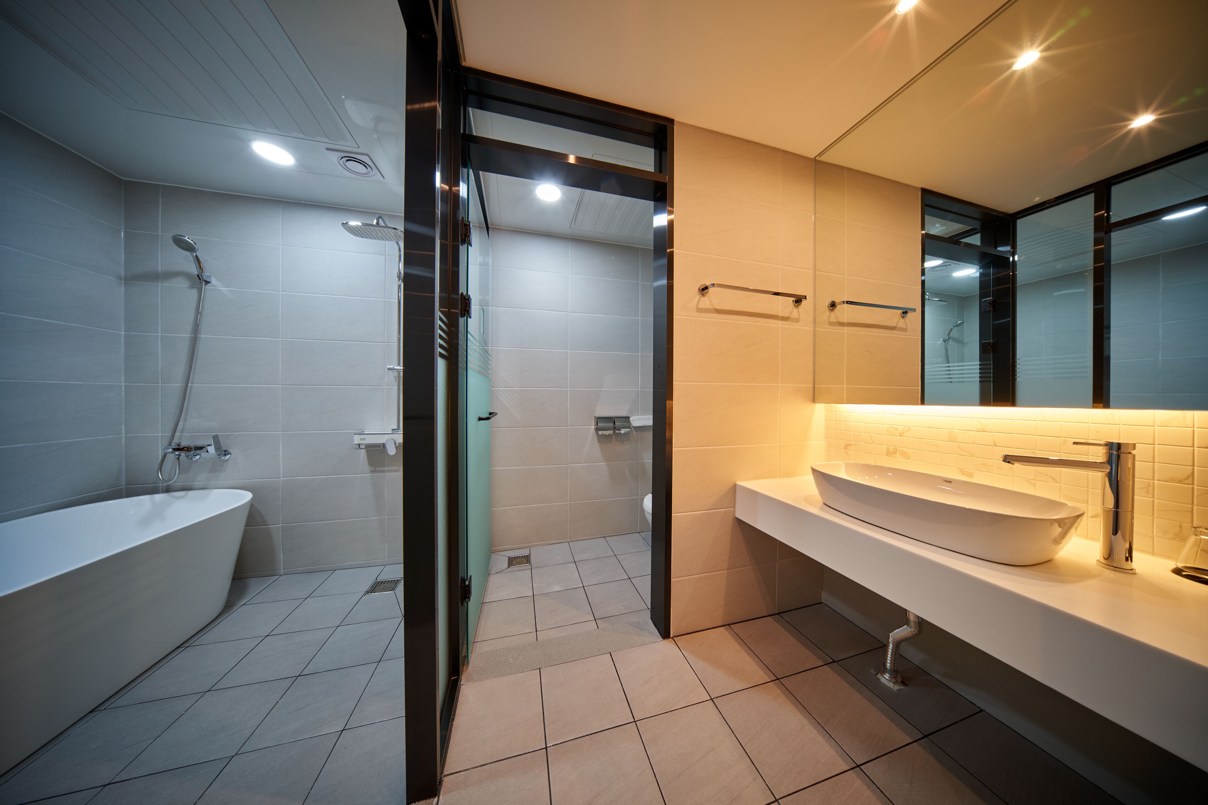 A modern bathroom with a freestanding bathtub, a glass-enclosed shower, and a large mirror above the sink.