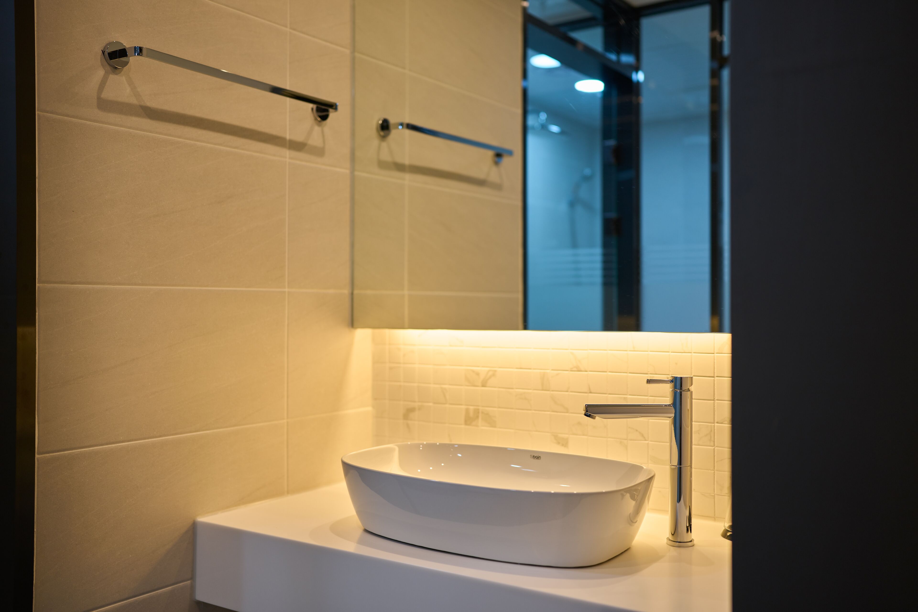 Un baño moderno con un lavamanos blanco tipo pedestal, grifo cromado y un perchero para toallas.