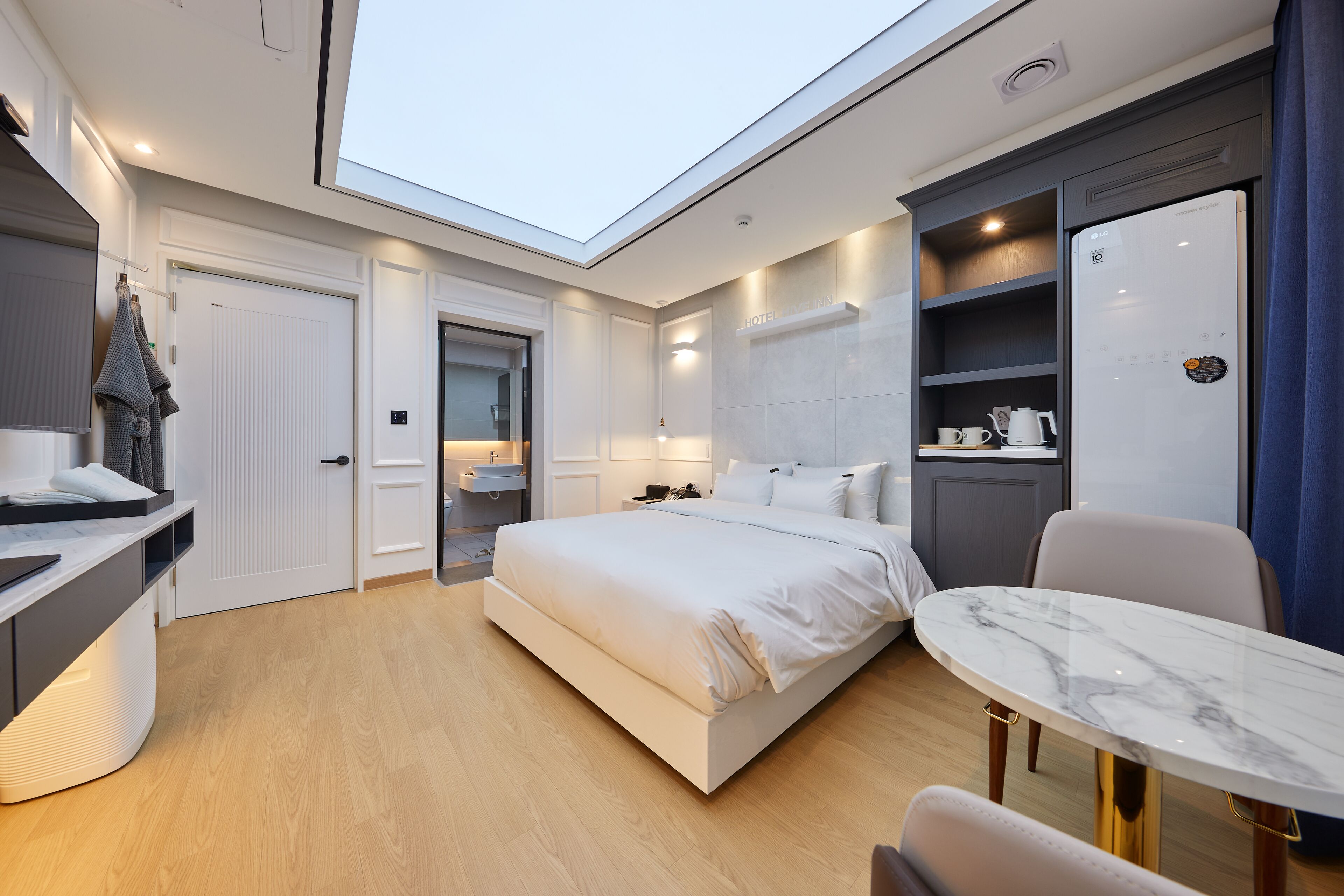 Ein modernes Hotelzimmer mit einem großen Bett, einem Schreibtisch, einem Esstisch und einer Küchenzeile.