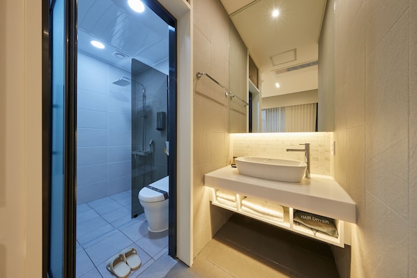 Un baño moderno con cabina de ducha de vidrio, un lavabo blanco y un espejo sobre el lavabo.