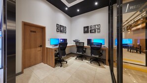 Escritório moderno com três mesas, cada uma com um monitor de computador, e uma porta com a inscrição 'Apenas para funcionários'.