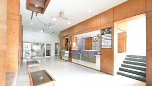 A spacious lobby with a reception desk, glass partitions, and a staircase leading to upper floors. - Hotel Kohinoor Plaza (Chhatrapati Sambhajinagar)