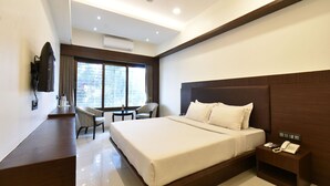 A modern hotel room with a large bed, a desk, a chair, and a nightstand with a phone. - Hotel Kohinoor Plaza (Chhatrapati Sambhajinagar)