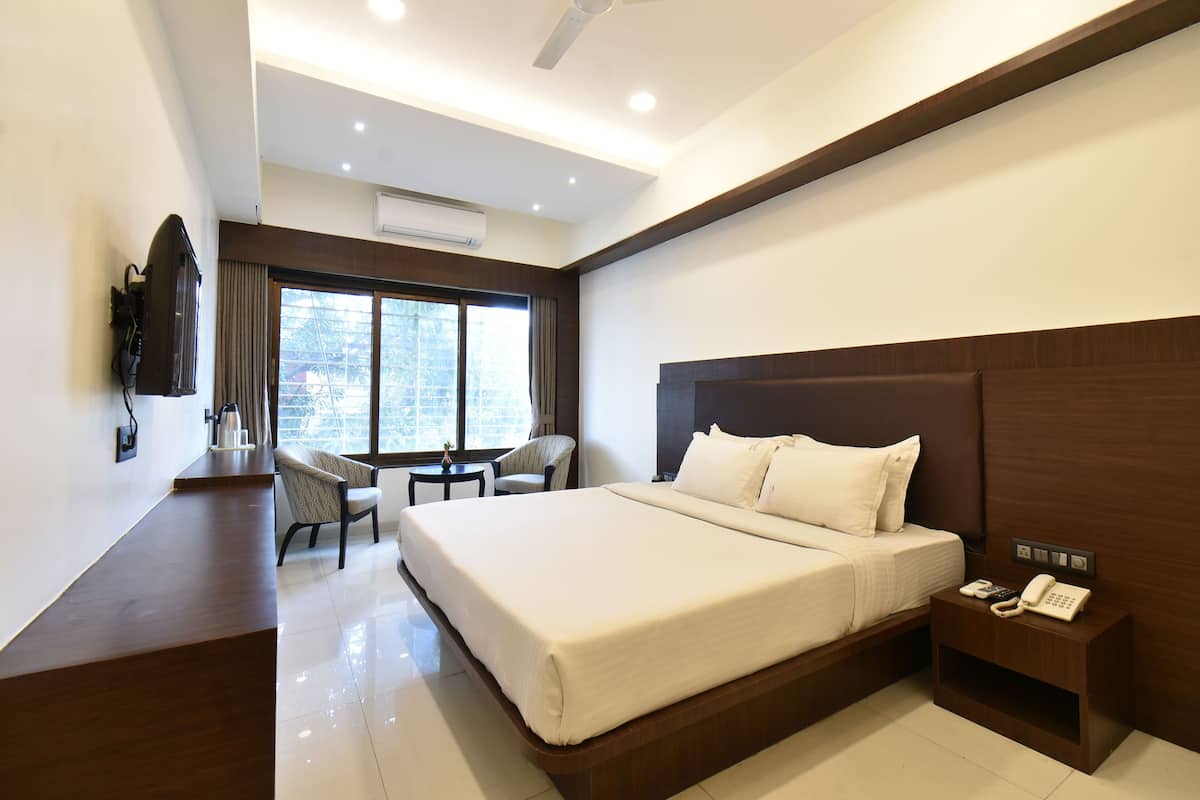 A modern hotel room with a large bed, a desk, a chair, and a nightstand with a phone.