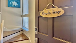 Une porte en bois avec une pancarte indiquant « Maison de plage » et une autre pancarte, placée au-dessus, qui souhaite la bienvenue.