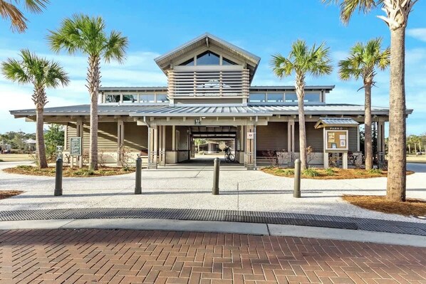 A modern building with a covered entrance, palm trees, and a sign labeled 'PARKING.'
