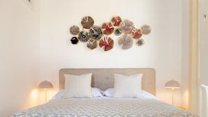 Een slaapkamer met een groot bed, twee bedlampjes en een wanddecoratie van ronde objecten.