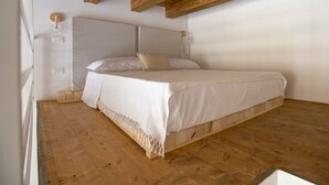 A bedroom with a wooden ceiling, a bed with white bedding, and a wooden floor. - Suite 2 Standard (Syracuse)