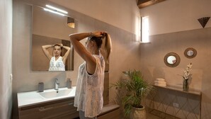 A modern bathroom with a large mirror, a sink, a vanity, and a potted plant. - Suite 7 Deluxe (Siracusa)
