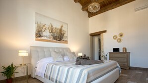 Un dormitorio con una cama grande, una mesita de noche con lámpara, un aparador y un espejo.
