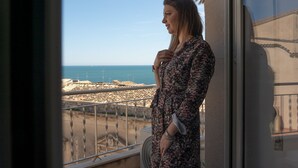 En balkong med utsikt över havet och en byggnad i bakgrunden.