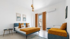 Ett modernt hotellrum med två sängar, ett litet bord och en balkong med gardiner.