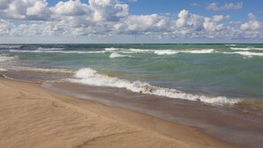 Une plage avec des vagues, un ciel dégagé et des nuages.