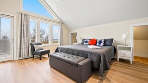 Une chambre à coucher avec un grand lit, un banc, une chaise et une table de chevet.