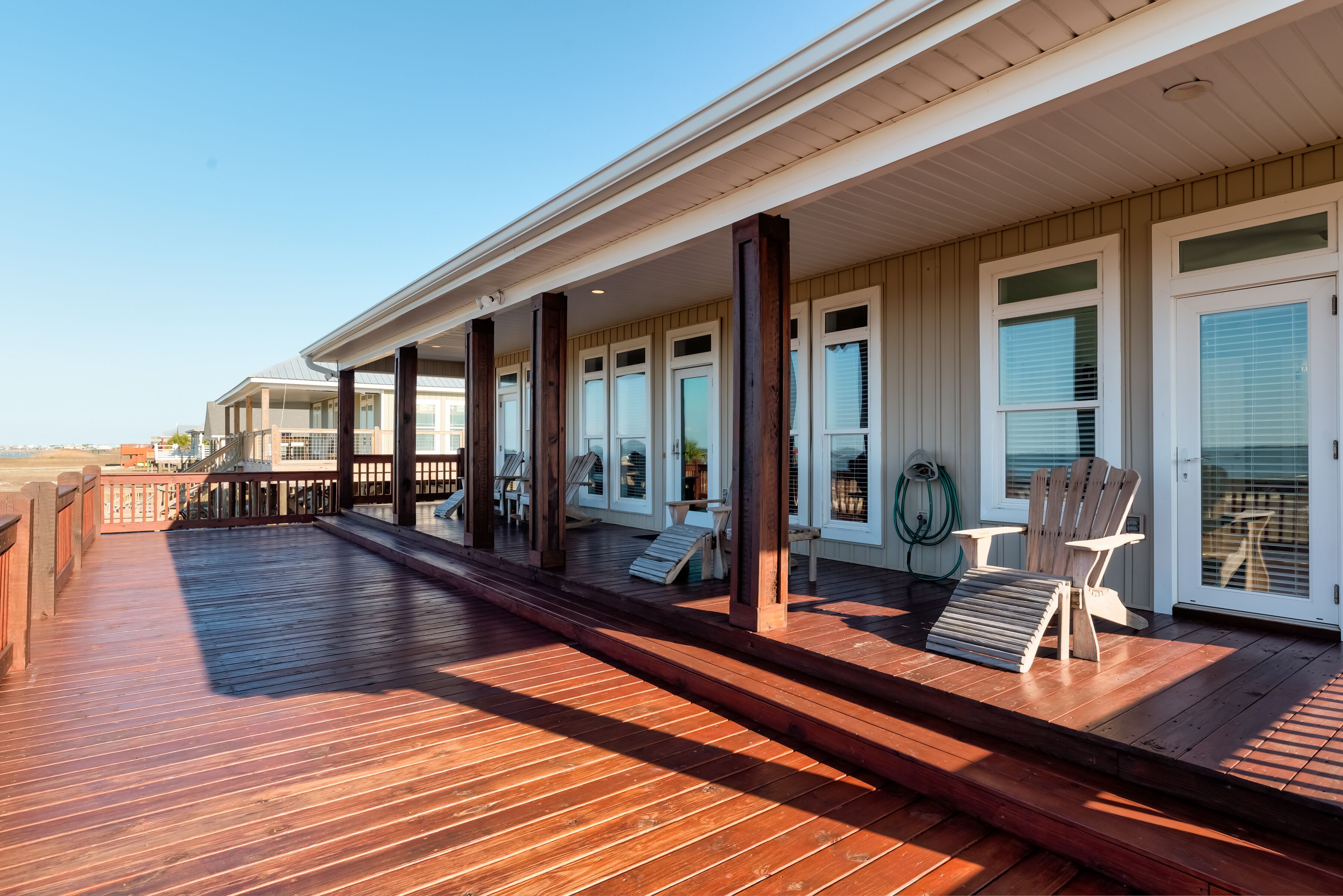 Une terrasse en bois avec des sièges extérieurs et un espace abrité doté de fenêtres.