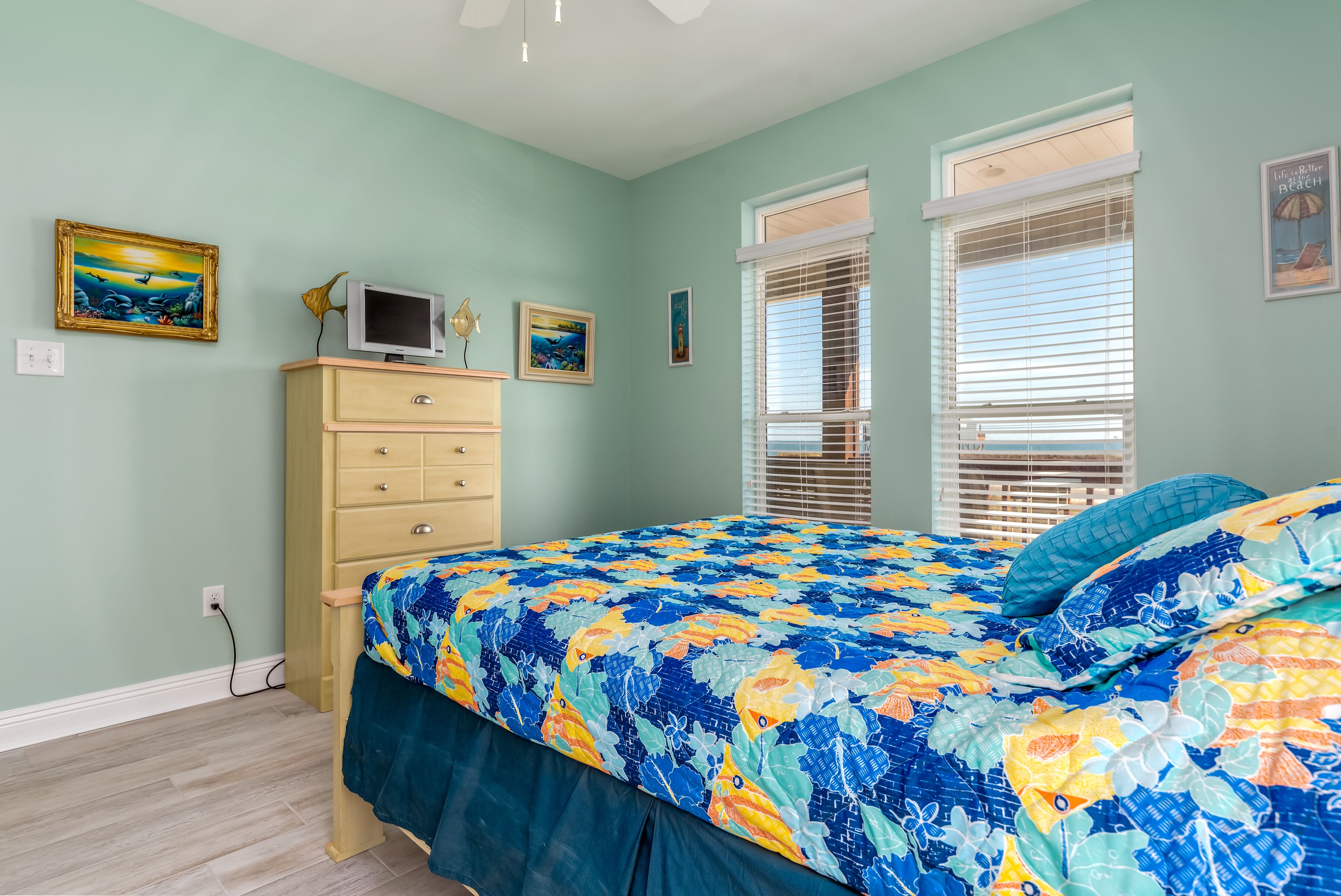 Ein Schlafzimmer mit Bett, Schminktisch und zwei Fenstern mit Jalousien.