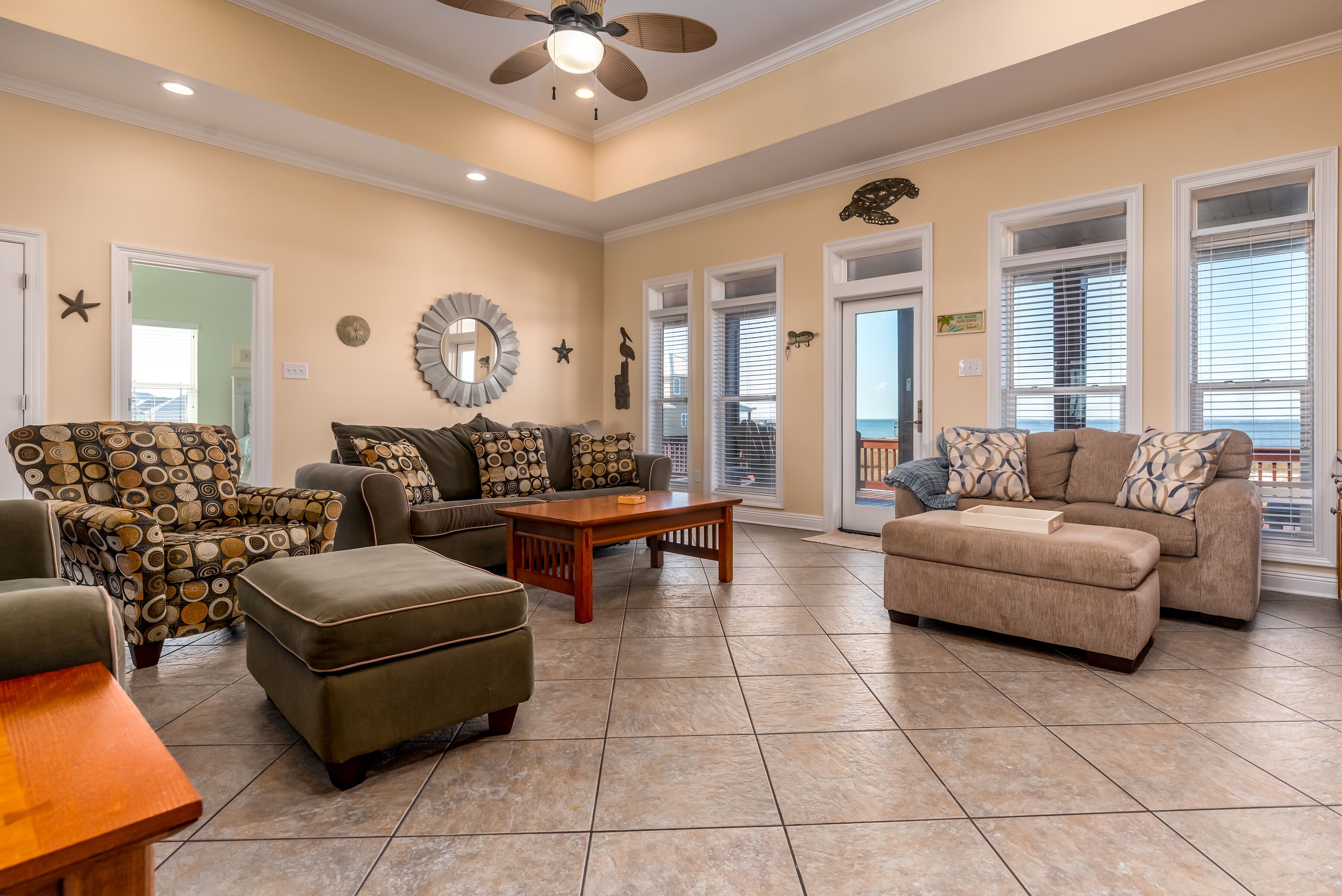 A spacious living room with a ceiling fan, a coffee table, and two sofas with patterned cushions.