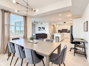 A modern kitchen with white cabinets, a black countertop, and a stainless steel refrigerator.