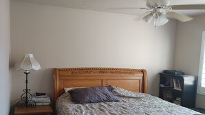 A bedroom with a wooden bed, a nightstand with a lamp, a ceiling fan, and a bookshelf. - #2 - Beautiful room with a view with a King bed (St. George)
