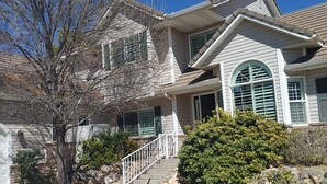 A two-story house with a covered front porch, a stone foundation, and a large tree in the front yard. - #2 - Beautiful room with a view with a King bed (St. George)