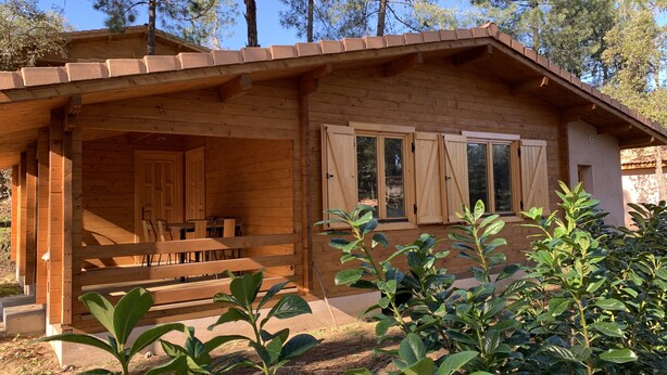A wooden cabin with a covered porch, a dining area, and a view of the surrounding forest. - Porticcio house near the sea (Grosseto-Prugna)