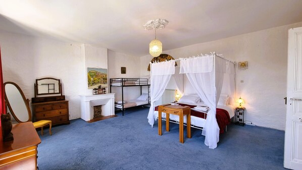 A bedroom with a bunk bed, a bedside table, a mirror, a dresser, and a painting on the wall.
