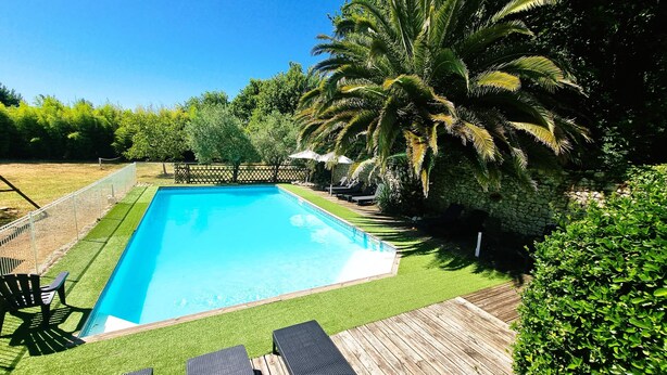 Ein rechteckiger Pool mit Holzterrasse und umlaufendem Kunstgrün.