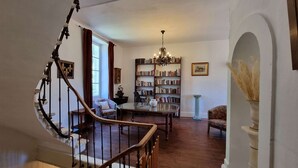 Eine Bibliothek mit Bücherregalen, einem Chandelier, einer Treppe und einem Fenster.