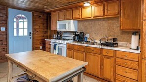 Une cuisine de style rustique, avec des murs en bois, un fourneau, un four à micro-ondes et des armoires en bois.
