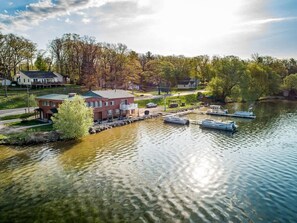 Une propriété au bord du lac, dotée d’un quai, de bateaux et d’une maison avec un toit rouge.