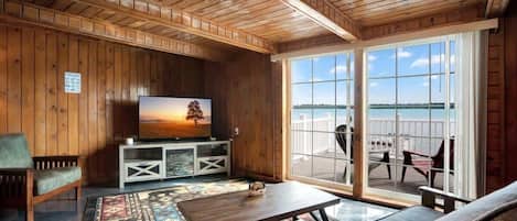 A wooden interior with a TV, sofa, and a view of the outdoors.