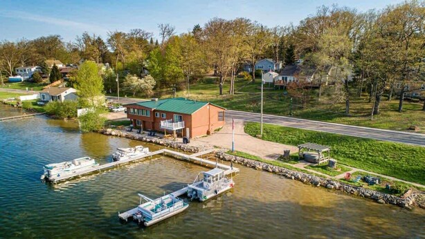 Une propriété au bord du lac, dotée d’un quai, d’un bâtiment avec un toit végétalisé et d’une zone herbeuse avec un sentier.