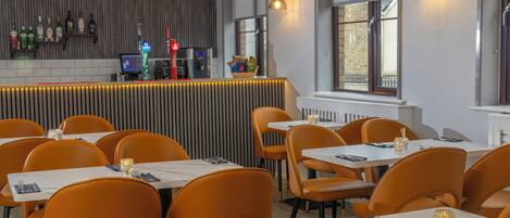 A restaurant with orange chairs, white tables, and a bar area with bottles and a cash register.