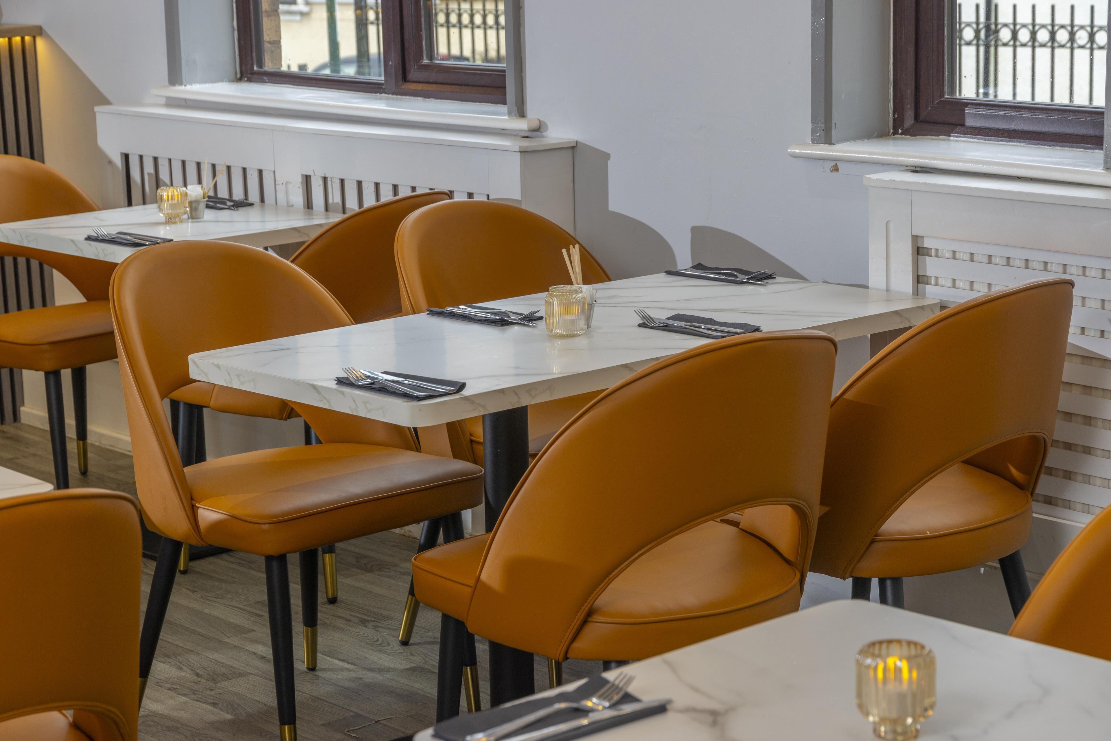 Ein Restaurantinnenraum mit Marmortischen, Ledersesseln und Blick aus dem Fenster.