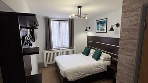 A modern bedroom with a large bed, a built-in wardrobe, a radiator, and a window with curtains. - Best Western Ebbw Vale (Ebbw Vale)