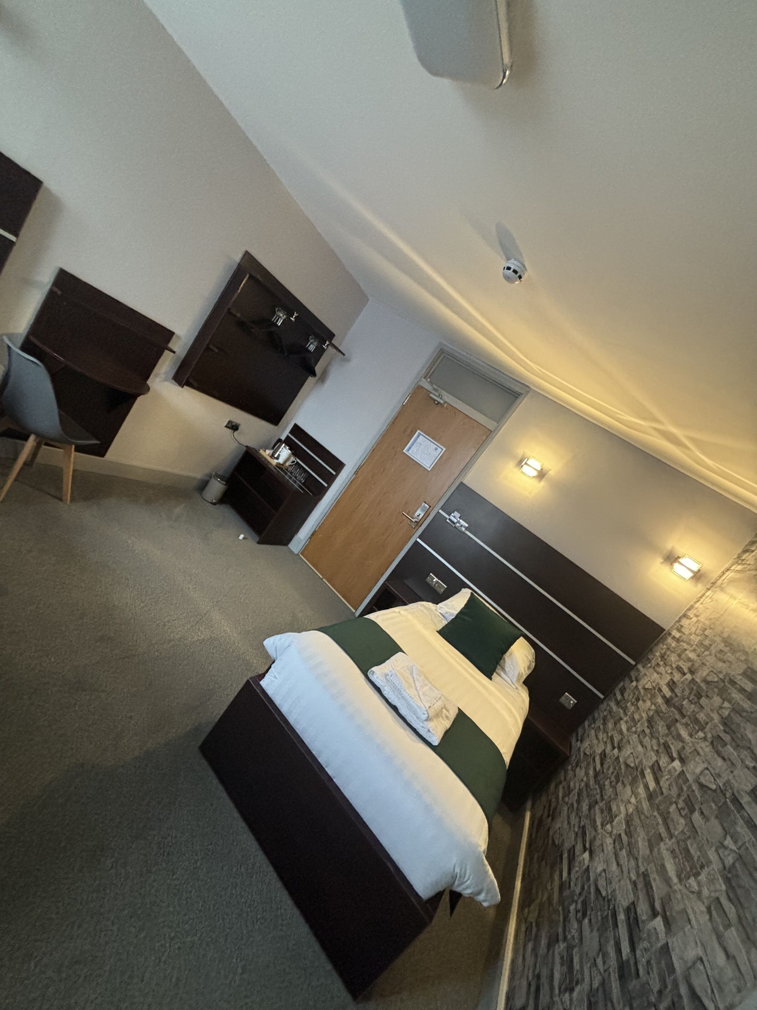 A hotel room with a bed, a desk, a chair, a wardrobe, and a bathroom.