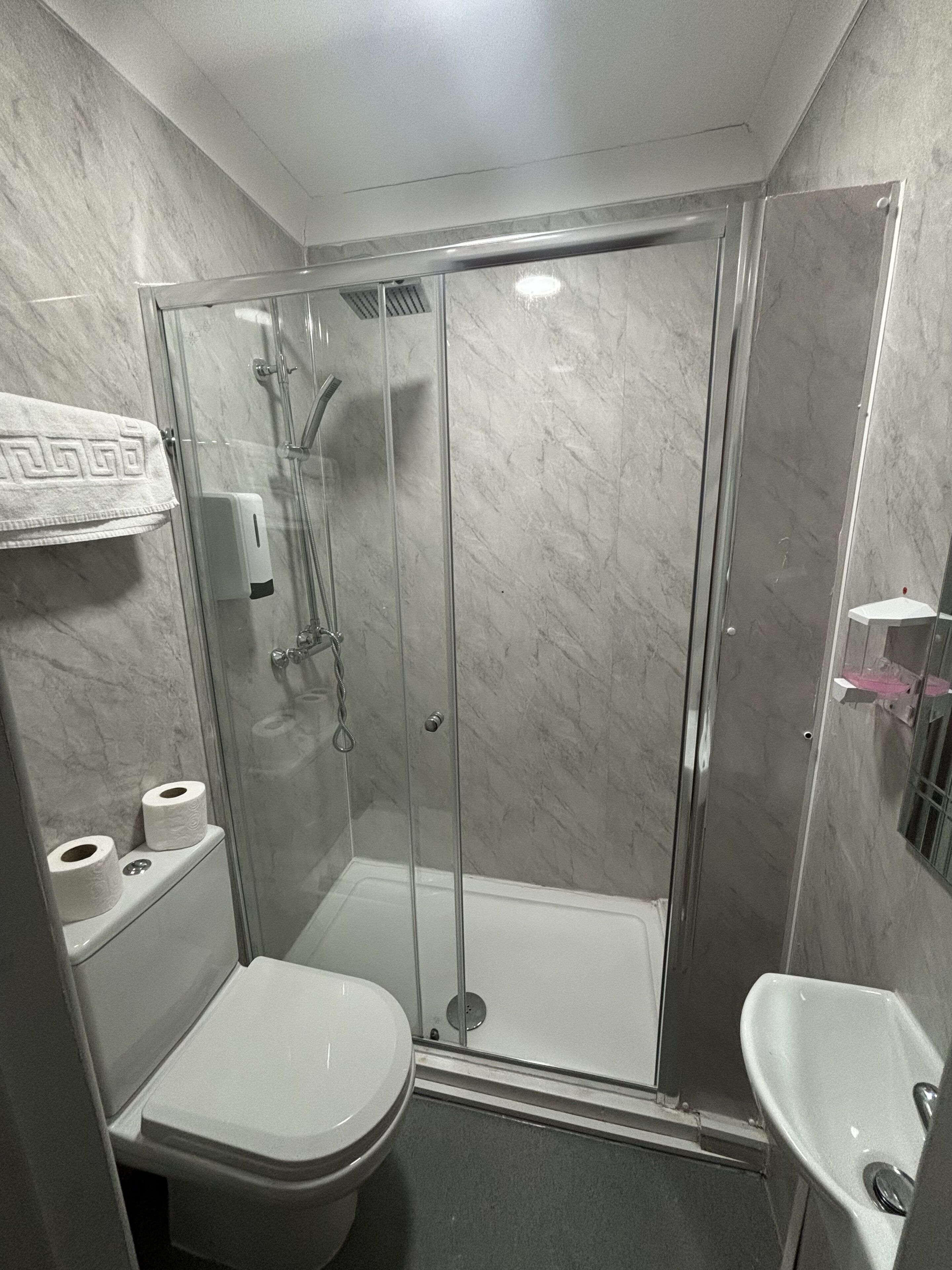 A bathroom with a glass-enclosed shower, a toilet, and a sink.