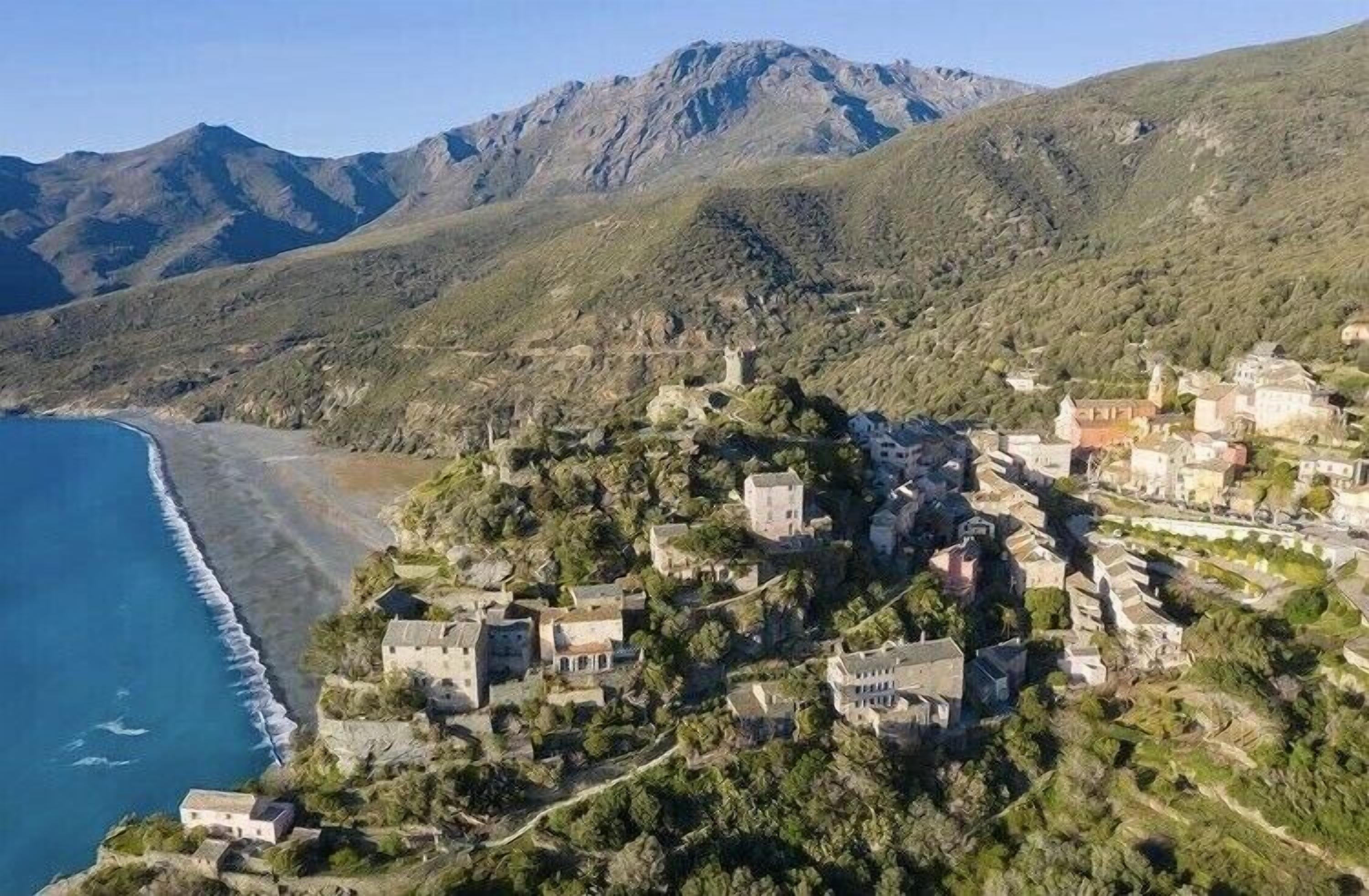 Uma vila costeira com edifícios numa encosta com vista para o mar.