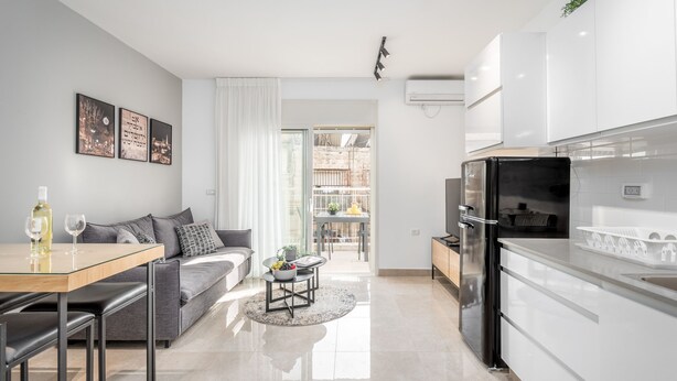 Une cuisine moderne avec des meubles blancs, un réfrigérateur noir et un coin repas comprenant une table et des chaises.